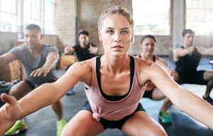 Shot of a group of people doing squats in a gym